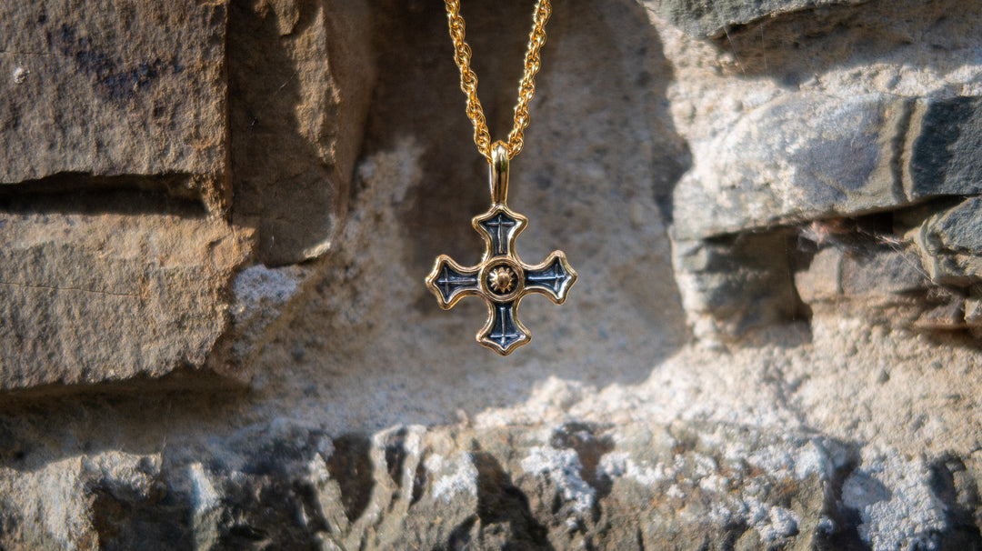 Gold necklace with a cross pendant on a stone wall