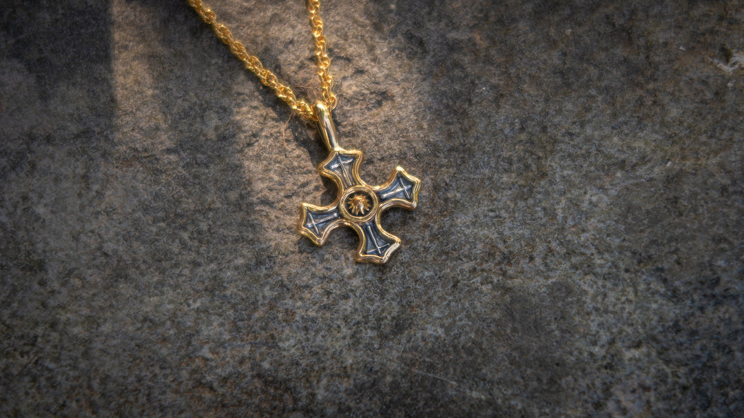 Gold and silver cross pendant on a textured dark background