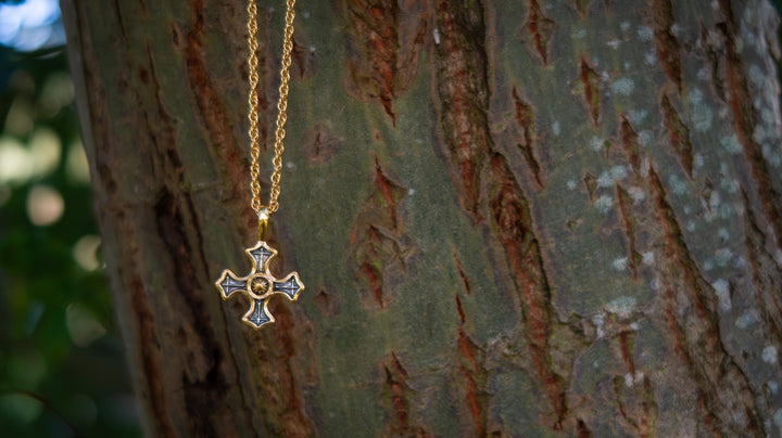 Gold necklace with a cross pendant on a tree trunk