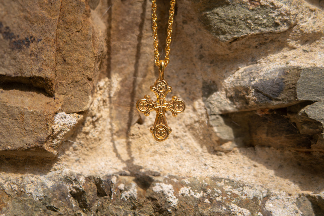 Gold cross necklace on a stone wall