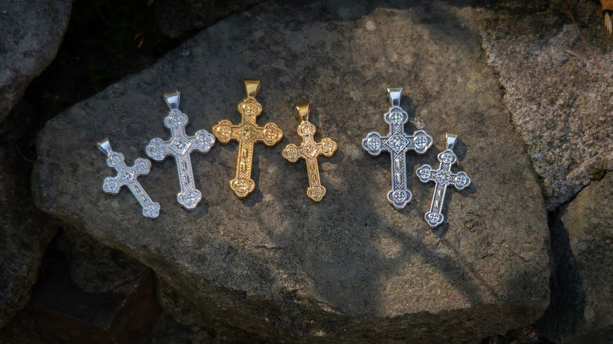 Five cross-shaped pendants on a textured stone surface