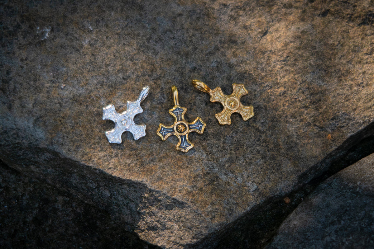 Three cross shaped pendants on a textured stone surface